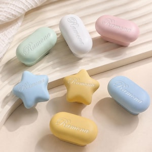 Peut inclure: Un ensemble de sept boutons de tiroir aux couleurs pastel, notamment vert menthe, blanc, rose, bleu clair et jaune. Les boutons sont en forme de rectangles arrondis ou d'étoiles à cinq branches, chacun portant le nom Ramona en relief.