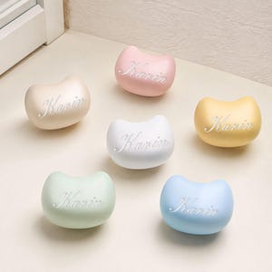 May include: Six smooth, bean-shaped objects in pastel colors including beige, pink, yellow, white, light green, and light blue. Each object features the name Karin embossed in a cursive script font on the front surface, creating a uniform collection.