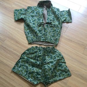 Peut inclure: Un ensemble deux pièces composé d'une chemise à manches courtes boutonnée et d'un short assorti à taille élastique. Les deux vêtements présentent un motif camouflage vert, marron et beige. La chemise a un col et une fermeture boutonnée sur le devant.