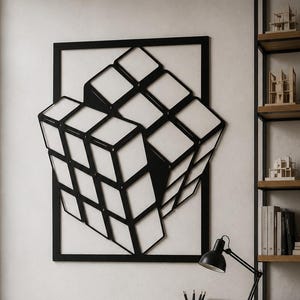 May include: A black metal wall art piece featuring a three-dimensional geometric cube design mounted on a white wall. The sculpture consists of a rectangular frame enclosing a stylized, multi-faceted cube structure with clean lines and open spaces.