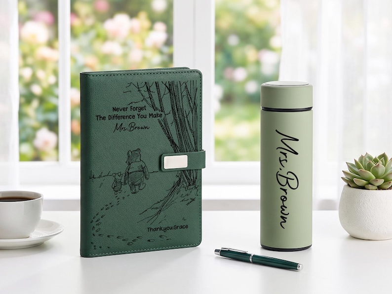 K&ouml;nnte beinhalten: Ein dunkelgr&uuml;nes Notizbuch mit einer Winnie Puuh-Illustration und dem Text Never Forget The Difference You Make Mrs. Brown Thank you Grace, eine hellgr&uuml;ne Isolierflasche mit dem Aufdruck Mrs. Brown und ein dunkelgr&uuml;ner Stift.