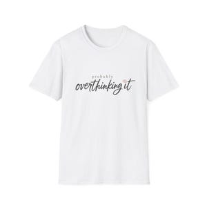 May include: A white short-sleeved t-shirt featuring the text "probably overthinking it" printed in black script and sans-serif font across the chest, accompanied by a small, simple pink line-art illustration of a human brain.