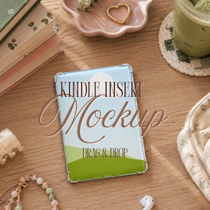 May include: A rectangular Kindle insert mockup featuring a clear plastic case over a graphic of a blue sky, a white sun, and green hills. The text KINDLE INSERT Mockup DRAG & DROP is printed in brown over the center of the graphic design.