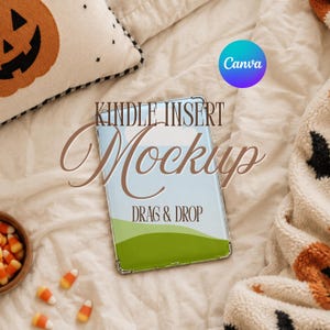 May include: A rectangular Kindle insert mockup featuring a light blue sky and green hills graphic. The text reads KINDLE INSERT Mockup and DRAG & DROP. The clear case is positioned on a white fabric surface with a pumpkin pillow and candy corn.
