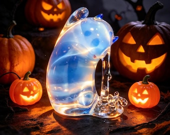 May include: A translucent, glowing blue glass cat figurine with a smooth, rounded form. The cat is depicted in a seated position with its head tilted downward, featuring subtle internal light diffusion and a clear, solid glass base.