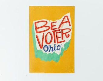 Peut inclure: Une affiche jaune avec un contour blanc de l'état de l'Ohio. Les mots "Be a Voter" sont écrits en lettres rouges et blanches à l'intérieur du contour. Le mot "Ohio" est écrit en lettres bleues sous le contour.