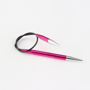 May include: A pair of circular knitting needles with a vibrant magenta shaft and silver tips, connected by a black flexible cable. The needles are designed for crafting and are set against a clean white background.