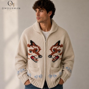 Può includere: Un cardigan in maglia color crema con cerniera, collo a scialle e due tasche frontali. Il maglione presenta due grandi motivi simmetrici di teste di volpe in marrone, nero e rosso, con impronte di zampe azzurre lungo l'orlo inferiore.