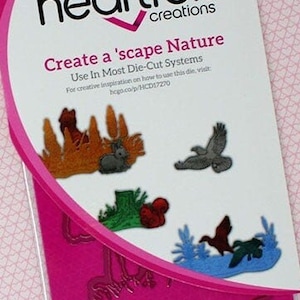 May include: A pink package of six heart felt creations craft dies for creating a nature scene. The package has the text "Create a 'scape Nature" and "Use In Most Die-Cut Systems".
