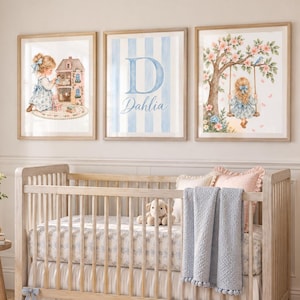 Könnte beinhalten: Ein Kinderbett aus hellem Holz mit weißem Rüschenrock, gemustertem Spannbettlaken und einer hellblauen, strukturierten Decke. Über dem Bett hängen drei gerahmte Wandbilder, die ein Kind mit Puppenhaus, den Buchstaben D und ein Kind auf einer Schaukel zeigen.