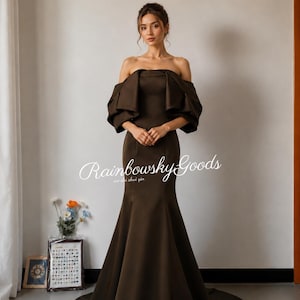 May include: A floor-length dark brown gown featuring an off-the-shoulder neckline with voluminous, pleated short sleeves and a fitted bodice that flares into a mermaid silhouette at the hem. The text Rainbowsky Goods is visible in white.