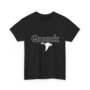 Può includere: Una t-shirt nera a maniche corte con il testo Quack in contorno bianco centrato sul petto. Sotto il testo si trova una silhouette bianca solida di un'anatra in volo. Il capo presenta un girocollo standard e un orlo dritto.