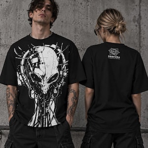 Könnte beinhalten: Ein schwarzes Kurzarm-T-Shirt mit einer großen weißen Grafik eines mechanischen Alien-Kopfes mit detaillierten Kabeln und Schaltkreisen. Auf der Rückseite befindet sich ein kleines weißes geometrisches Logo mit dem Text OBSCURA UNIDENTIFIED ARCHIVE.