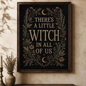 May include: A rectangular framed wall art piece featuring a black background with gold-colored text that reads, THERE'S A LITTLE WITCH IN ALL OF US. The text is surrounded by an intricate botanical border of leaves, flowers, and crescent moons.