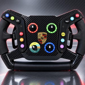 May include: A black carbon fiber racing steering wheel featuring a central Porsche logo, multiple colorful circular buttons labeled with text including HB, RAD, CRK, ACK, RVS, F+, TC/AT, TC/LONG, MAP, ABS, WIP, DRK, and PIT, and black rubberized grips.