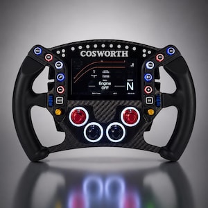 May include: A black carbon fiber racing steering wheel featuring a central digital display with the text COSWORTH and Engine OFF. The wheel includes numerous multi-colored buttons, rotary dials, and ergonomic black grips on both sides.