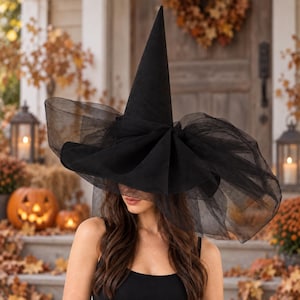 Peut inclure: Un chapeau noir haut et pointu doté d'un large bord structuré, orné de couches de tulle noir transparent et volumineux qui se drapent autour de la base et s'étendent vers l'extérieur, créant une silhouette dramatique et superposée.