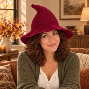 May include: A deep burgundy, pointed hat with a wide, flexible brim. The hat features a textured, knit-like surface and a distinct, slightly curved peak at the top, providing a structured yet soft appearance for this headwear accessory.