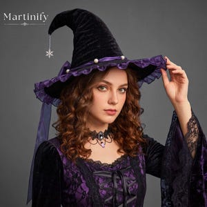 May include: A black velvet pointed hat featuring a purple ruffled trim, a purple ribbon band with white pearl accents, and a silver snowflake charm hanging from the tip. The word Martinify is printed in the upper left corner of the image.