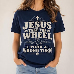 May include: A navy blue short-sleeve t-shirt featuring a distressed white graphic print. The design includes a cross, a winding road, and the text: JESUS TAKE THE WHEEL I TOOK A WRONG TURN. The shirt has a crew neckline and a standard fit.