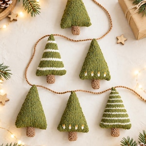 Op de afbeelding: Een decoratieve slinger met zes gebreide groene kerstboomhangers aan een bruin koord. De bomen variëren in ontwerp, waarbij sommige effen groen zijn, andere witte horizontale strepen hebben en weer andere kleine witte stippen tonen.