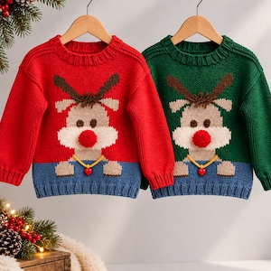 Peut inclure: Deux pulls en tricot à manches longues, un rouge et un vert, arborant chacun un motif de renne avec un nez en pompon rouge, des bois marron et un petit collier jaune avec un pendentif cœur rouge, terminés par un ourlet côtelé bleu.
