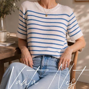 May include: A short-sleeved knit jumper featuring a cream base with horizontal blue stripes, a round neckline, and ribbed trim at the collar and sleeves. The jumper is paired with light blue denim jeans. The text Vanya Nest is overlaid.