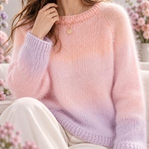 May include: A long-sleeved knit sweater featuring a soft gradient color transition from light peach at the neckline to a vibrant pink in the center, ending in a light purple hue at the ribbed cuffs and hemline with a fuzzy texture.