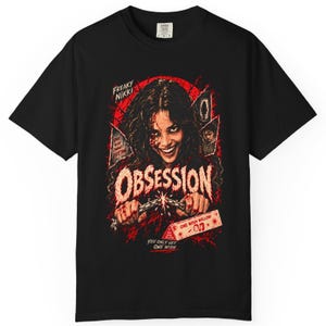 May include: A black short-sleeve t-shirt featuring a graphic print of a person with a wide smile. The design includes red splatters, the text "FREAKY NIKKI", "OBSESSION", "ONE WISH CHANGES EVERYTHING", "ONE WISH WILLOW", and "YOU ONLY GET ONE WISH".