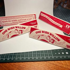 May include: Three rectangular red and white paper boxes labeled ONE WISH WILLOW. The packaging features illustrations of two faces, star motifs, and the text Spark the middle and break in half, Amaze your friends, and You only get ONE WISH.