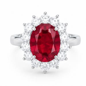 Könnte beinhalten: Ein silberner Ring mit einem großen, oval geschliffenen, tiefroten Edelstein in der Mitte, umgeben von einem Kranz aus zwölf runden, klaren Brillanten. Die Ringschiene ist glatt und poliert und verleiht der Fassung ein klares, metallisches Finish.