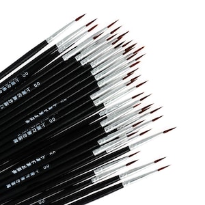 Könnte beinhalten: Eine Sammlung von Feinmalpinseln mit schwarzen Holzstielen, silbernen Metallzwingen und braunen Synthetikborsten. Jeder Stiel ist mit der Nummer 00 und chinesischen Schriftzeichen in weißer Schrift bedruckt und fächerförmig angeordnet.