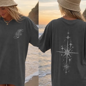 May include: A charcoal grey short-sleeve t-shirt and a tan bucket hat. The front of the shirt features a small white graphic of hands and text. The back of the shirt displays a large, vertical white starburst design with multiple pointed stars.