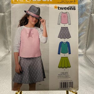 May include: New Look sewing pattern 6241 for tweens, sized U.S. 8-16. The envelope features a light pink and gray raglan sleeve top with a star design and a patterned skirt. Illustrations show four garment variations including tops and skirts.