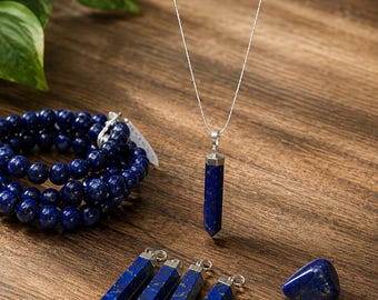 May include: A collection of lapis lazuli jewelry including a beaded bracelet, four hexagonal point pendants with silver-toned bails, one loose tumbled stone, and a single hexagonal point pendant hanging from a thin silver-toned chain necklace.
