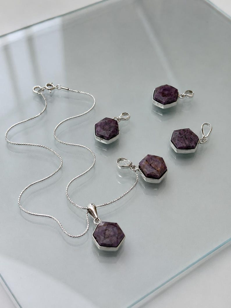 May include: A silver necklace with a hexagonal purple gemstone pendant and four matching hexagonal purple gemstone charms, each set in a silver frame with a small silver bail for attachment, featuring a delicate silver chain with a spring ring clasp.