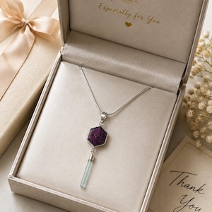 May include: A silver necklace featuring a hexagonal purple stone pendant with a dangling light blue cylindrical crystal. The jewellery is presented in a beige gift box with the gold text Especially for You printed on the inside lid.