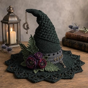 May include: A dark green crocheted pointed hat featuring a textured basketweave pattern, adorned with dark purple and green crocheted flowers, fern leaves, a grey ribbon with black beads, moon phase charms, and a hanging owl and key pendant.