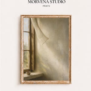Könnte beinhalten: Ein gerahmter Kunstdruck mit der Aufschrift MORVENA STUDIO PRINTS zeigt ein Fenster mit einem nach innen wehenden, transparenten Vorhang, eine kleine Schale auf dem Sims und Sonnenlicht, das Schatten auf eine strukturierte, beige Wand wirft.
