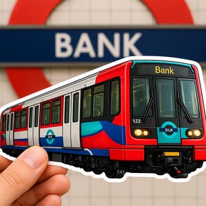 Op de afbeelding: Een gestanste sticker met een rode, witte en talingkleurige DLR-trein met het nummer 122 en de tekst Bank op het voorste display. Het treindesign bevat het DLR-logo aan de zijkant en voorkant, tegen een achtergrond van een wazig metrostationbord.