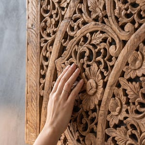K&ouml;nnte beinhalten: Ein rechteckiges Wandpaneel aus Holz mit aufwendigen, handgeschnitzten Blumen- und Blattmustern. Das naturfarbene, hellbraune Holz zeigt ein detailliertes Reliefdesign mit symmetrischen Motiven und einer durchgehend strukturierten Oberfl&auml;che.
