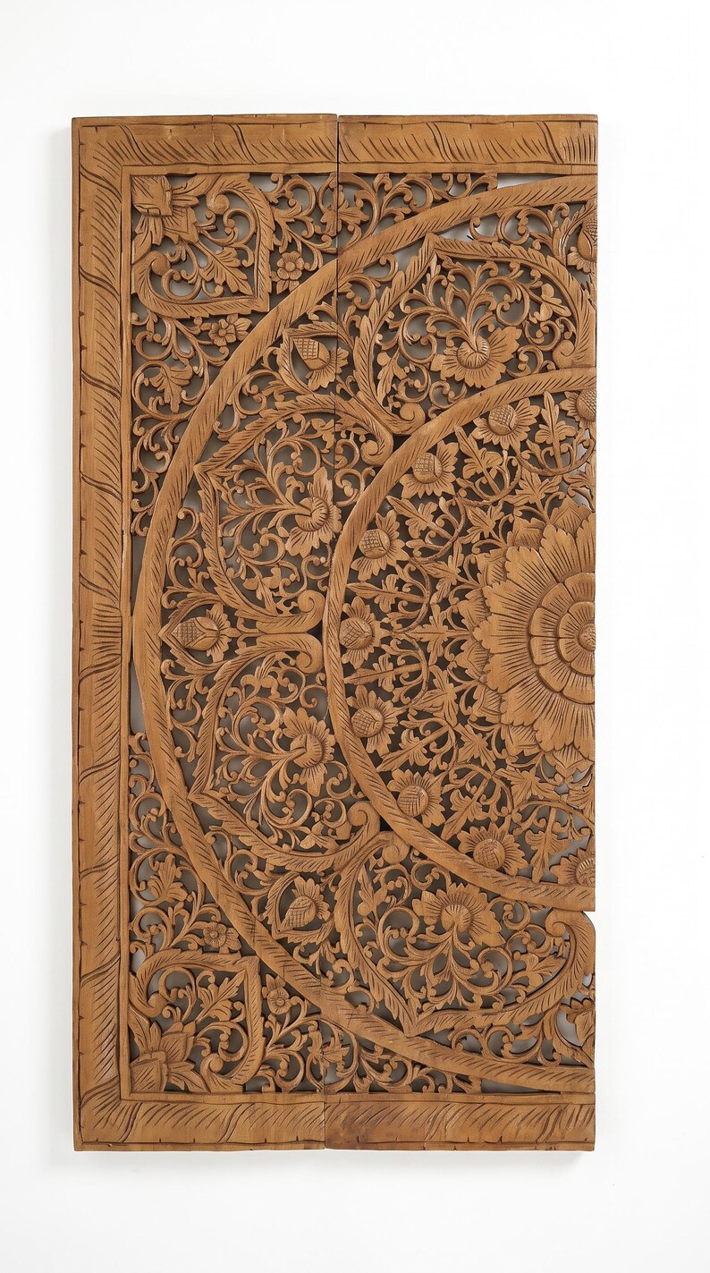 K&ouml;nnte beinhalten: Ein rechteckiges Wandpaneel aus hellbraunem Holz mit detaillierten, handgeschnitzten Blumen- und Blattmotiven. Das Design zeigt ein gro&szlig;es, zentrales kreisf&ouml;rmiges Muster mit geschichteten Bl&uuml;tenbl&auml;ttern und Ranken, umrahmt von einer geraden Bord&uuml;re mit seilartiger Struktur.