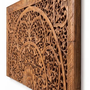 K&ouml;nnte beinhalten: Ein rechteckiges Wandpaneel aus Holz mit aufwendigen, handgeschnitzten Blumen- und Rankenmotiven. Das Design umfasst ein zentrales halbkreisf&ouml;rmiges Bogenmuster mit detaillierten Bl&uuml;tenbl&auml;ttern und Bl&auml;ttern, umrahmt von einer Kante mit linearen Schnitzereien.