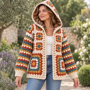 May include: A hooded cardigan constructed from multi-coloured granny square crochet motifs in shades of cream, mustard yellow, burnt orange, and teal blue. The garment features long sleeves with cream-coloured ribbed cuffs and an open front design.