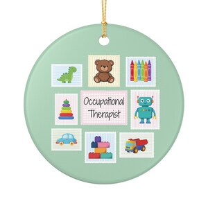 Könnte beinhalten: Ein rundes, hellgrünes Keramikornament mit einem zentralen rechteckigen Etikett mit dem Text Occupational Therapist. Um das Etikett herum befinden sich acht kleine quadratische Illustrationen eines Teddybären, Buntstiften, Dinosauriers, Roboters, Spielzeugautos, Lastwagens, Bausteinen und eines Stapelrings.