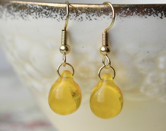 May include: A pair of gold dangle earrings with yellow glass teardrop shaped beads.