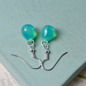 May include: A pair of silver dangle earrings with light blue teardrop-shaped stones.