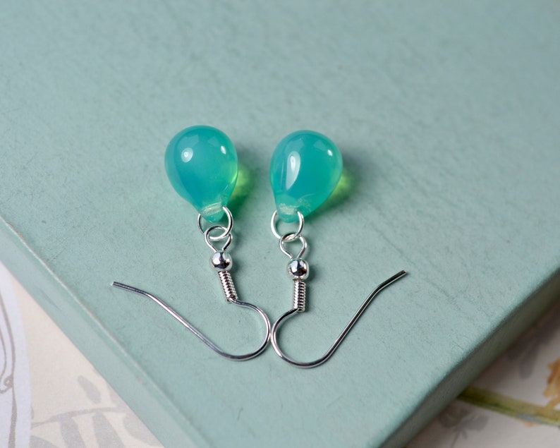 May include: A pair of silver dangle earrings with light blue teardrop-shaped stones.