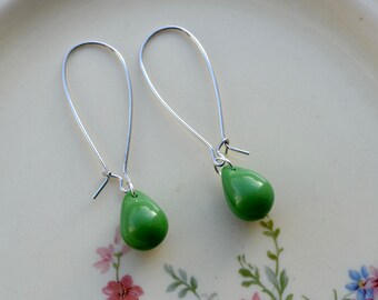 May include: A pair of silver dangle earrings with green teardrop-shaped beads.
