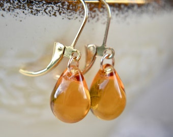 May include: A pair of gold dangle earrings with amber teardrop-shaped glass beads.